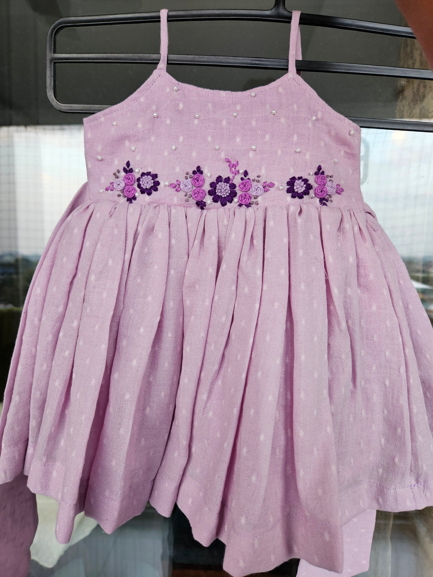 Lovely Lavender spaghetti-strap dress with hand embroidery hanging outdoors.
