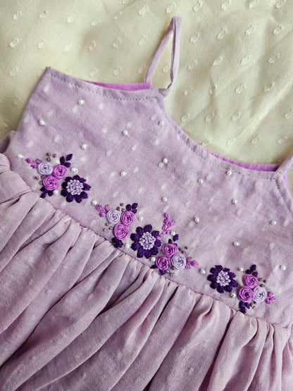 Close-up of purple floral embroidery and pearl details on moss cotton.