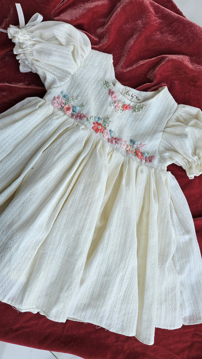 ivory Gardenia dress with hand-embroidered floral detailing on a red backdrop.