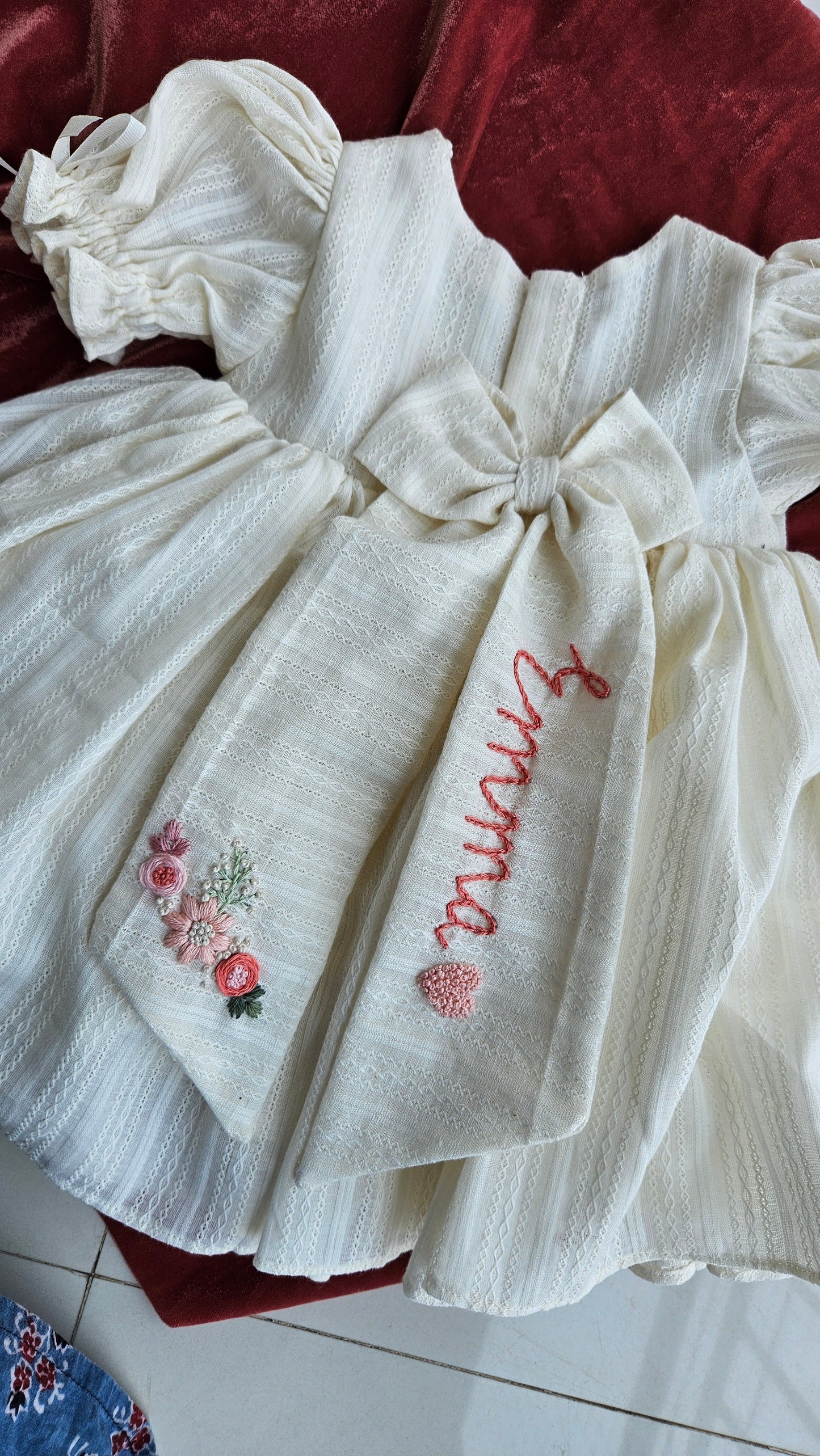 Back view of Gardenia dress showing custom embroidered name bow and floral detailing.`