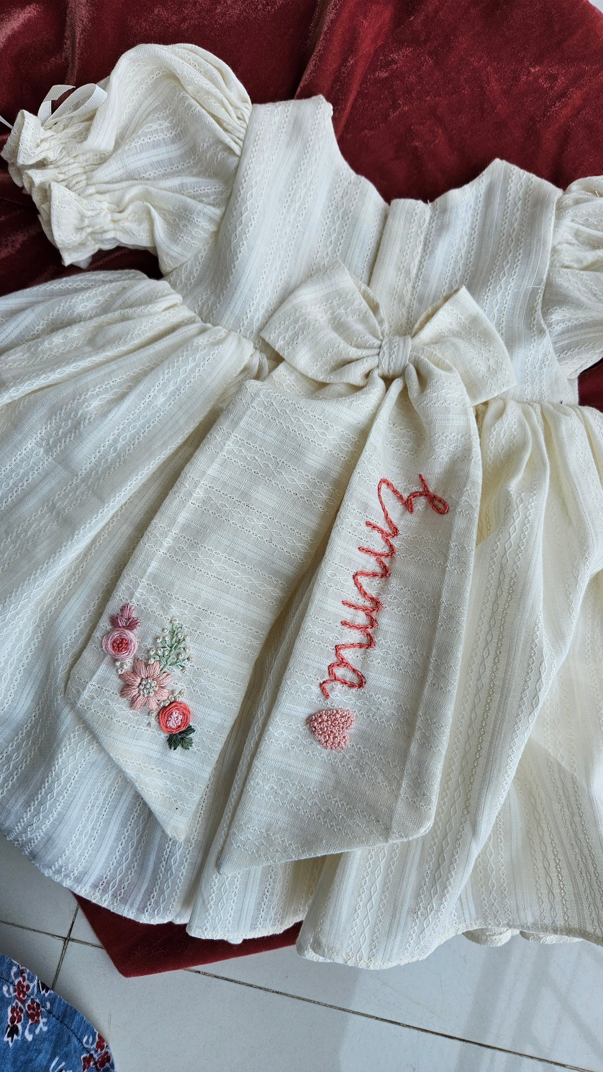 Back view of Gardenia dress showing custom embroidered name bow and floral detailing.`
