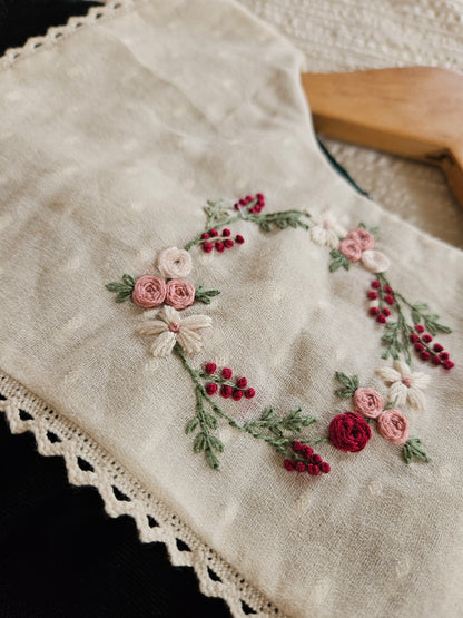 Close-up of embroidered floral wreath on ivory yoke of velvet dress 