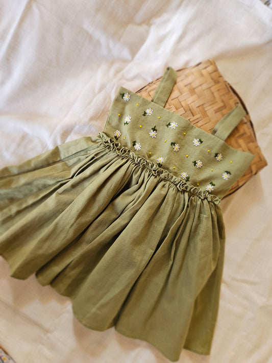 Handmade sage baby dress with daisy embroidery laid flat
