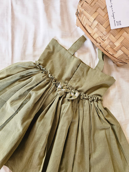 Green dress with decorative straps on a white surface