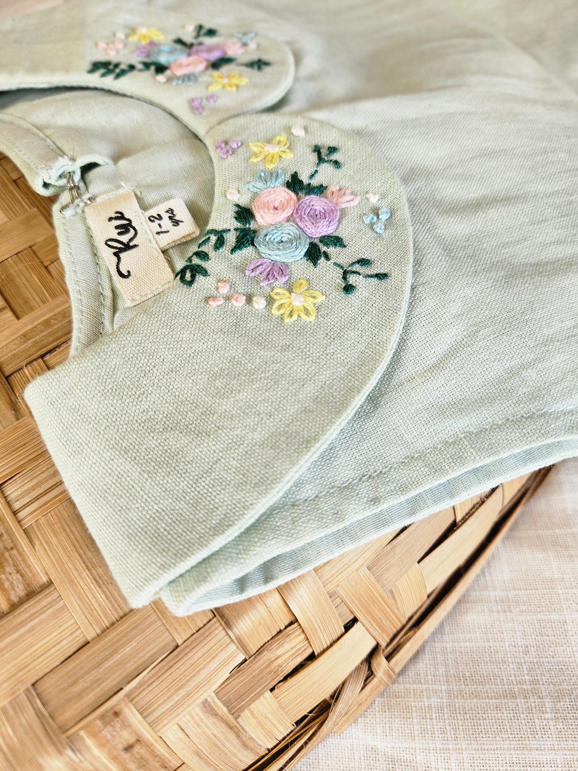 Close-up of floral embroidery on sage baby dress collar