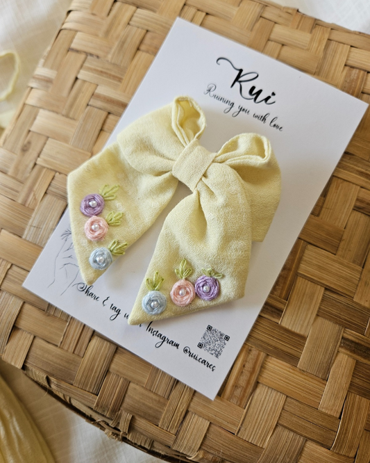 “Handmade yellow embroidered sailor bow displayed on woven basket – Rui.care