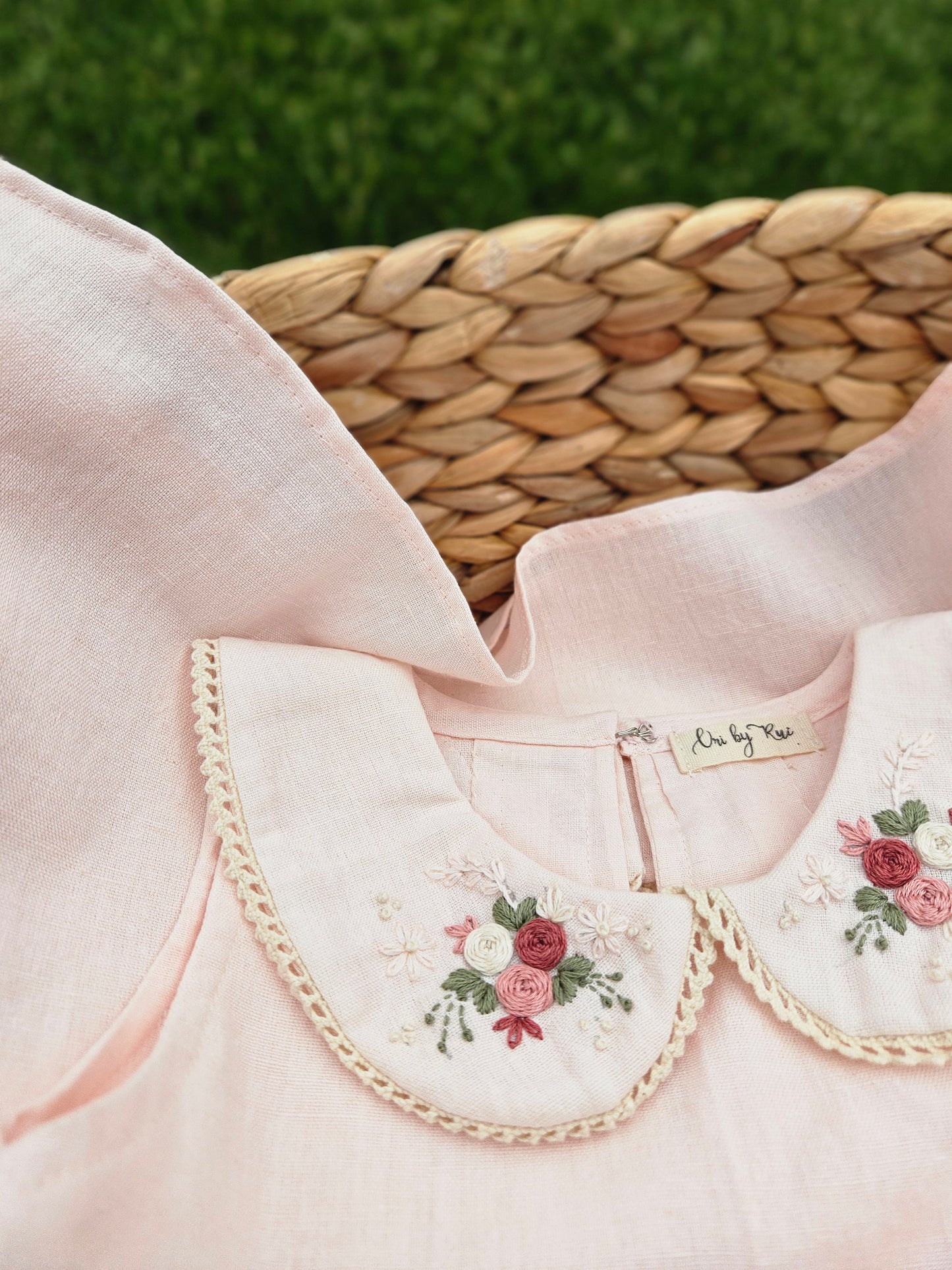 A baby pink cotton linen A-line dress for girls featuring a hand-embroidered Peter Pan collar with delicate pink floral embroidery and scalloped trim. The sleeveless dress has a classic silhouette, making it perfect for birthdays, festive occasions, family outings, and special celebrations.