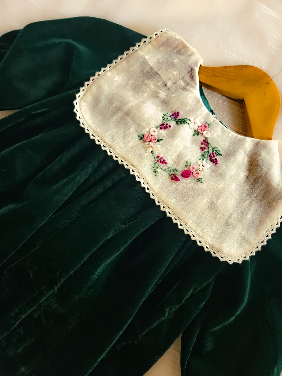 Detailed embroidery on lace-trimmed ivory yoke of emerald velvet dress