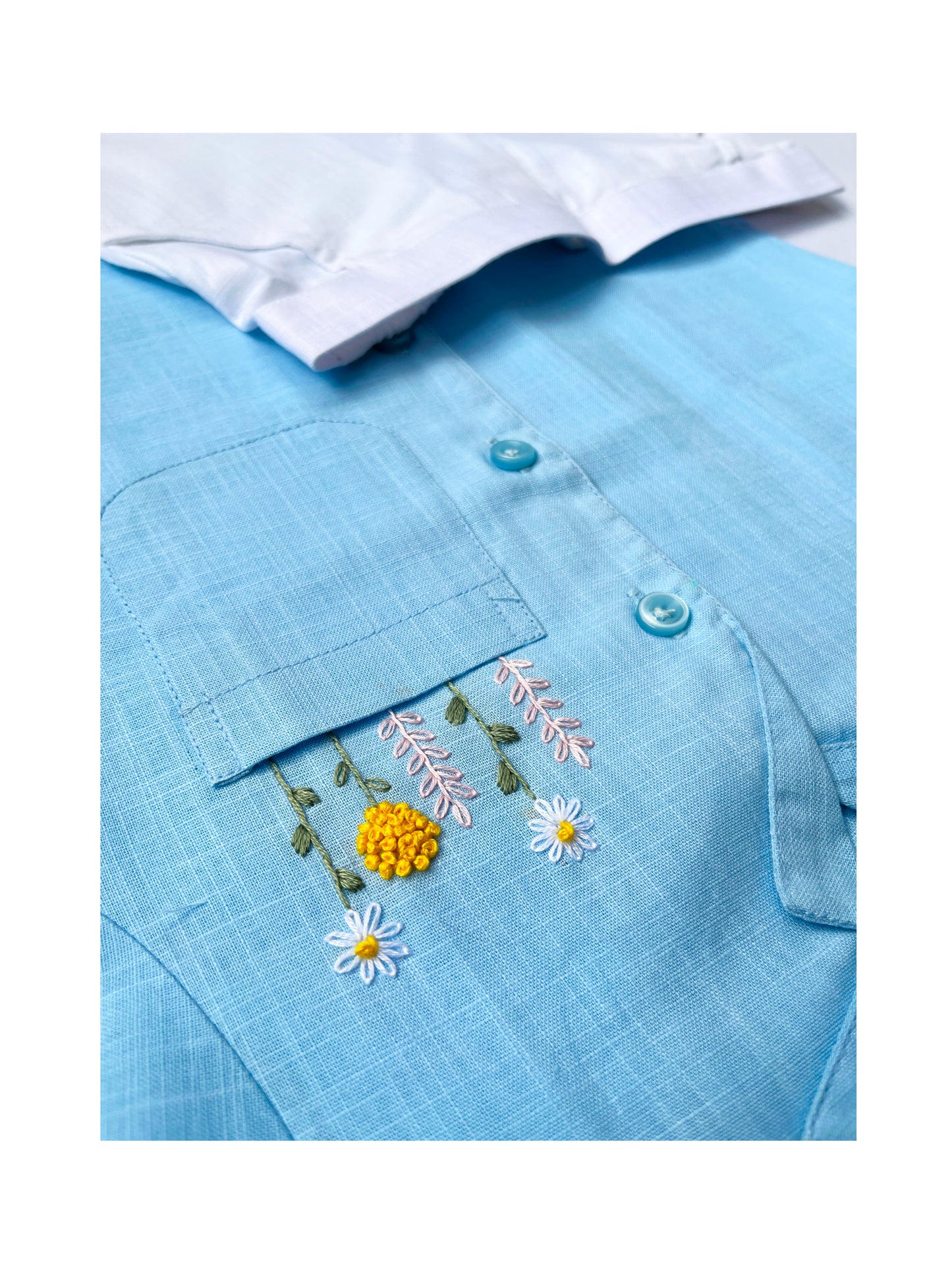 Flatlay of Peeka-Blue shirt paired with white shorts on a blue floral background.