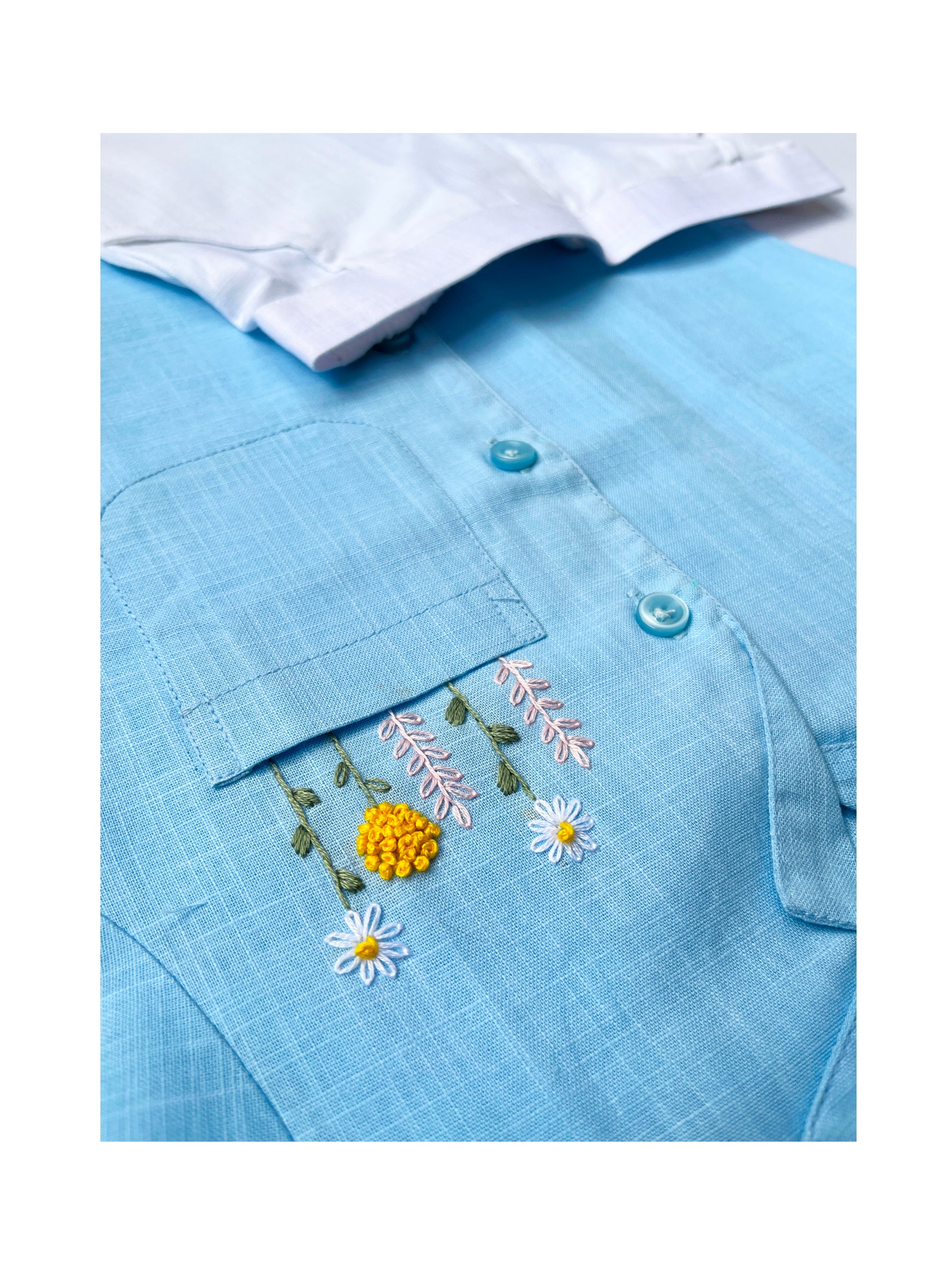 Flatlay of Peeka-Blue shirt paired with white shorts on a blue floral background.