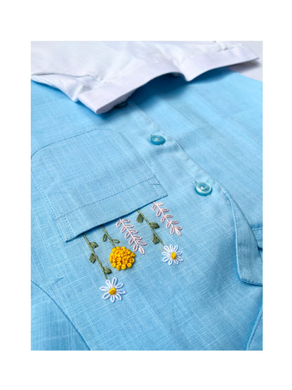 Flatlay of Peeka-Blue shirt paired with white shorts on a blue floral background.