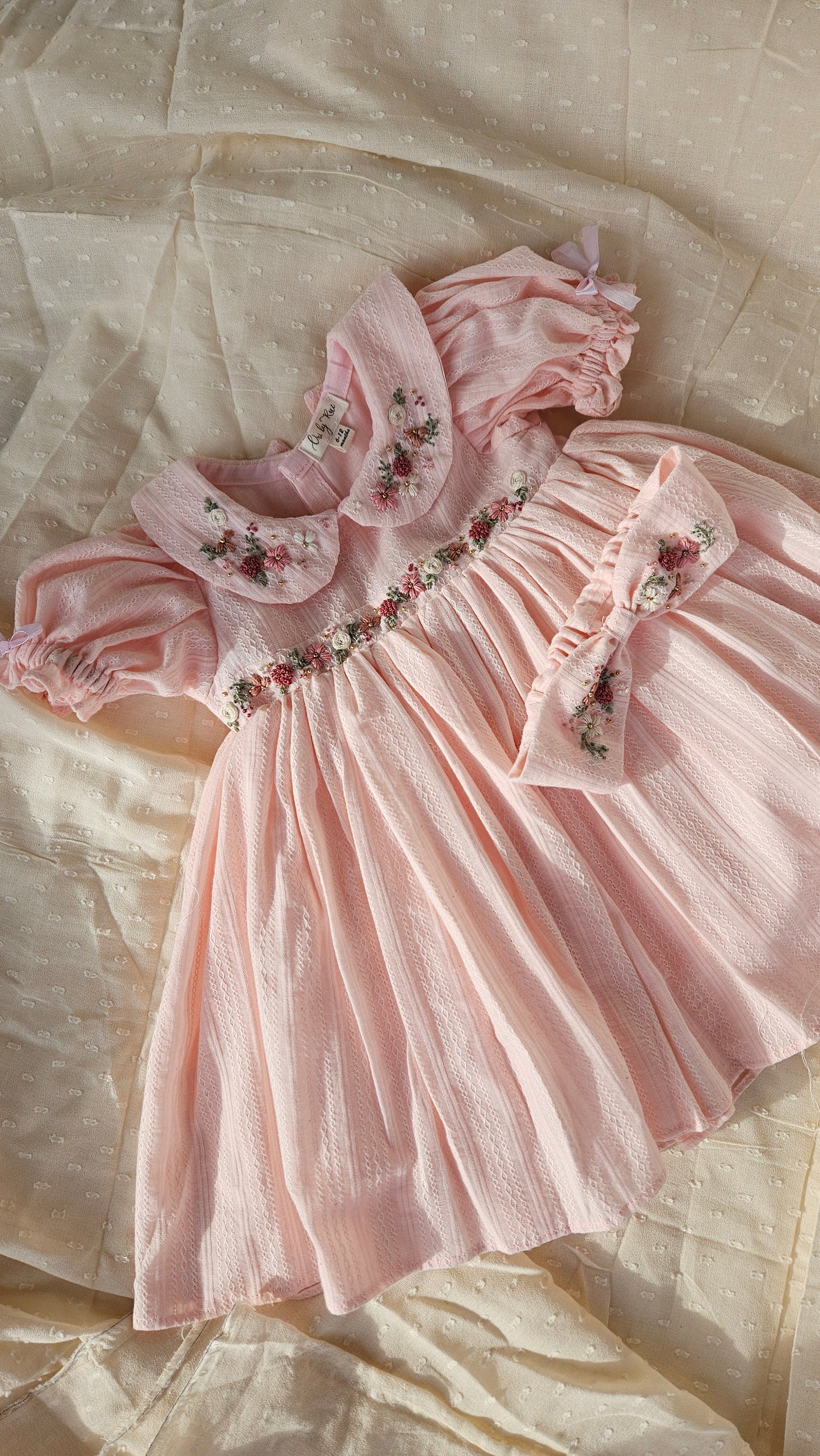 Flatlay of Peachy Peep dress showing floral embroidery and matching bow.
