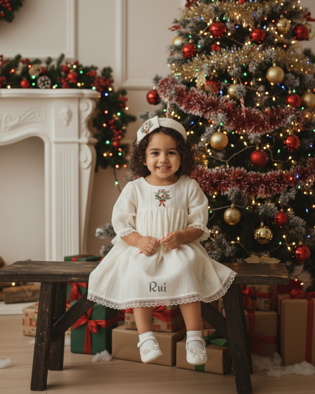 Toddler girl in ivory festive dress sitting near Christmas tree