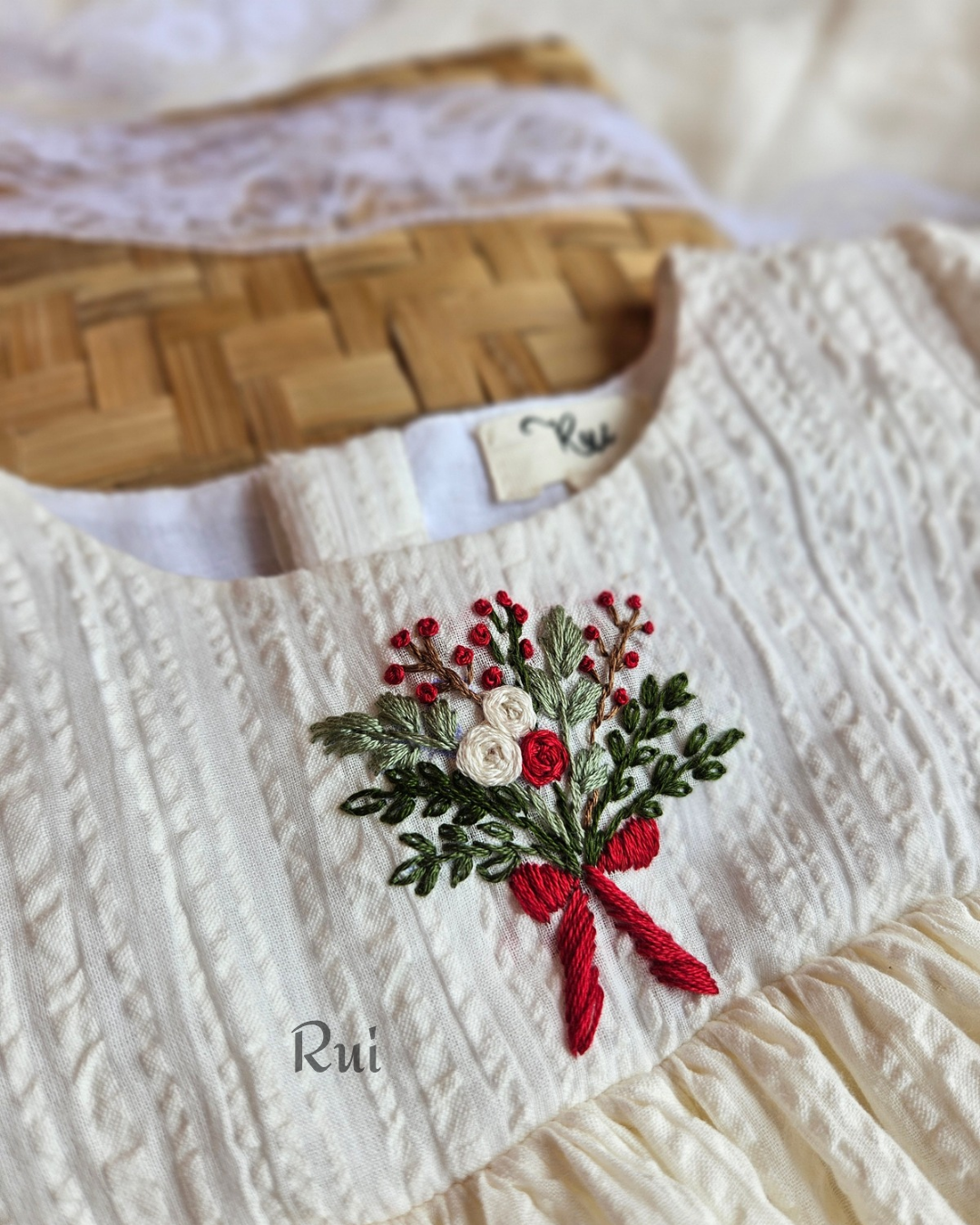 Close-up of hand-embroidered floral bouquet motif on ivory Christmas dress – Rui.care