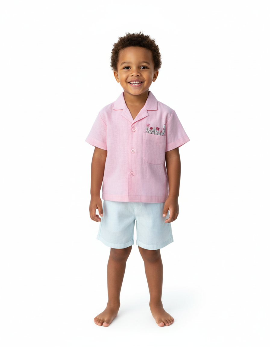 Boy wearing Bubble Gum embroidered shirt and blue shorts smiling in a studio.